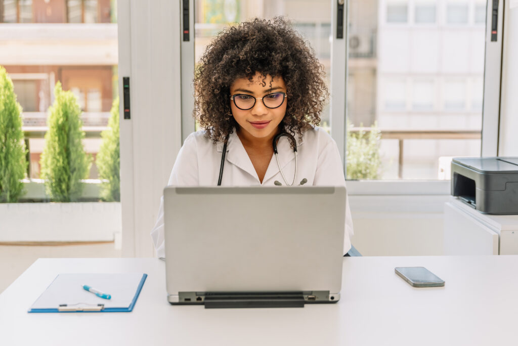 Smiling female doctor using laptop at medical clinic